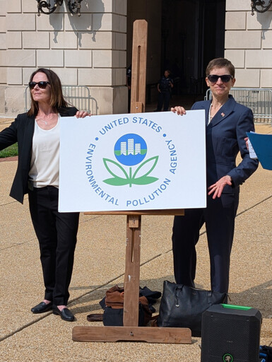 photograph of two women by a sign reading Environmental Pollution Agency outside the EPA