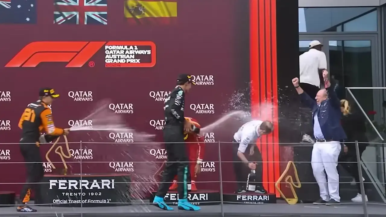 Podium celebrations after the Austrian GP. Piastri and Russell are spraying champagne, while Hans Zimmer holds his arms in the air and cheers them on.
